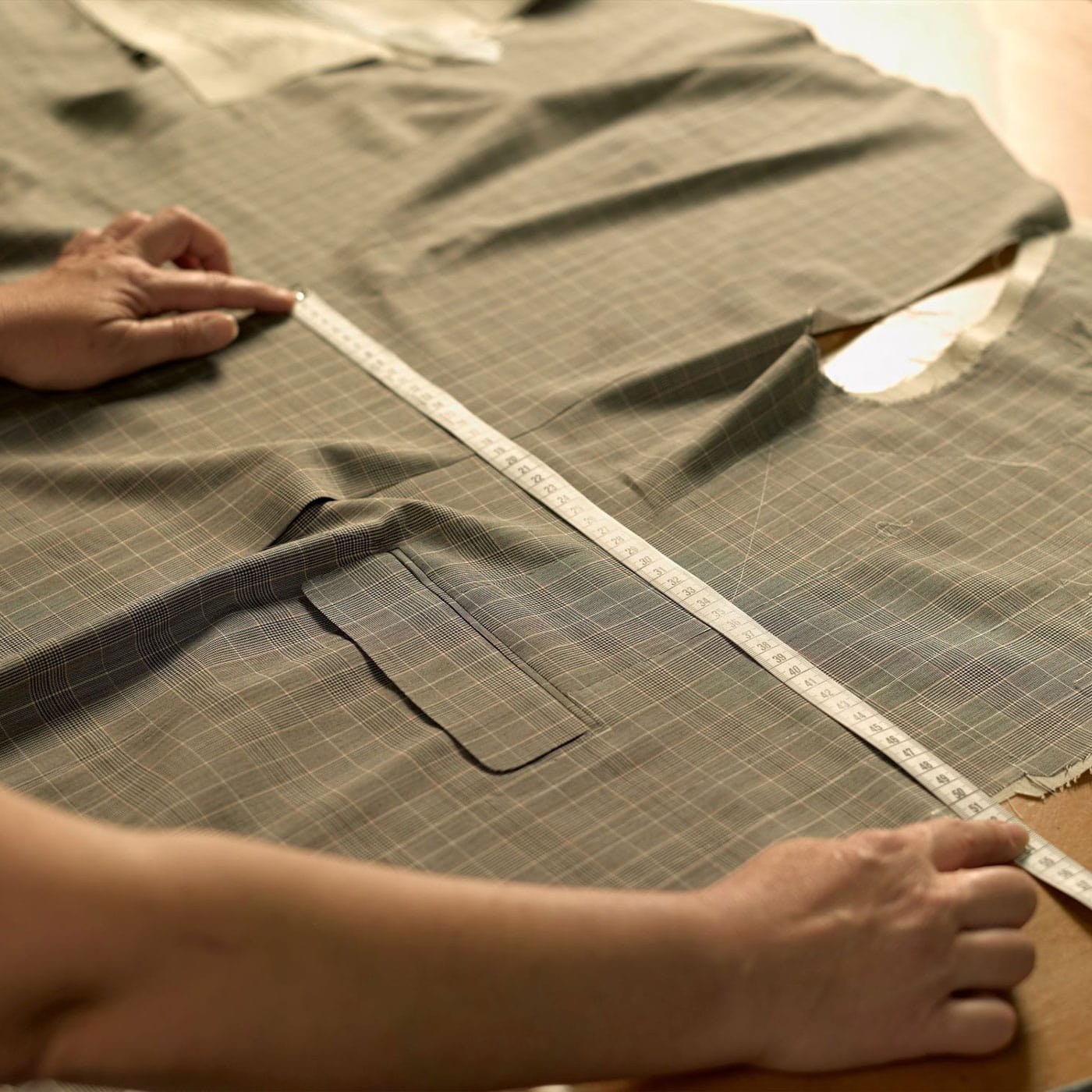The pieces of a Belvest tailored waistcoat are laid out on a table, being measured by a tailor.