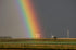 A rainbow over a field with wind turbines in the distance