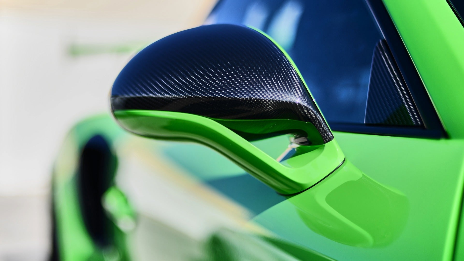 A green supercar in close-up on the wing mirror and trailing body